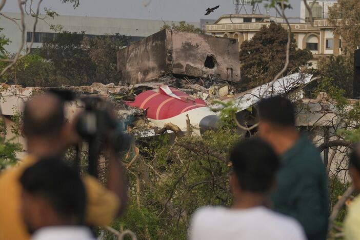 Onlookers watch wreckage from Thursday's Air India plane crash lying atop a building in Ahmedabad, India, on Saturday.