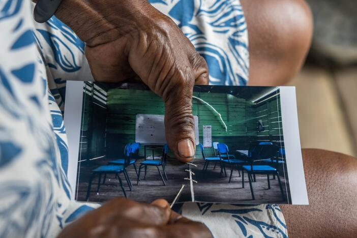 Margarita Rojas Mena stitches up a torn photo of the local school, where armed groups had a confrontation — part of a healing ritual for residents. She's a healer in Mojaudó, a community in Alto Baudó, Chocó, Colombia.
