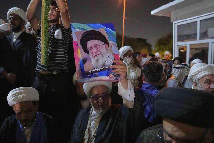 An Iraqi Shia cleric holds a portrait of Iran's Supreme Leader Ayatollah Ali Khamenei during a protest against Israeli attacks on multiple cities across Iran, at a bridge leading to the fortified Green Zone where the U.S. Embassy is located in Baghdad, Iraq, Thursday.