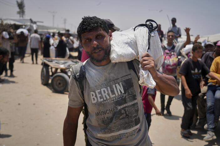 Omar al-Hobi, 43, from Rafah, carries a bag of food he collected at a distribution center run by private contractor the Gaza Humanitarian Foundation in the southern Gaza Strip, as he arrives at his tent in Khan Younis, on June 10.