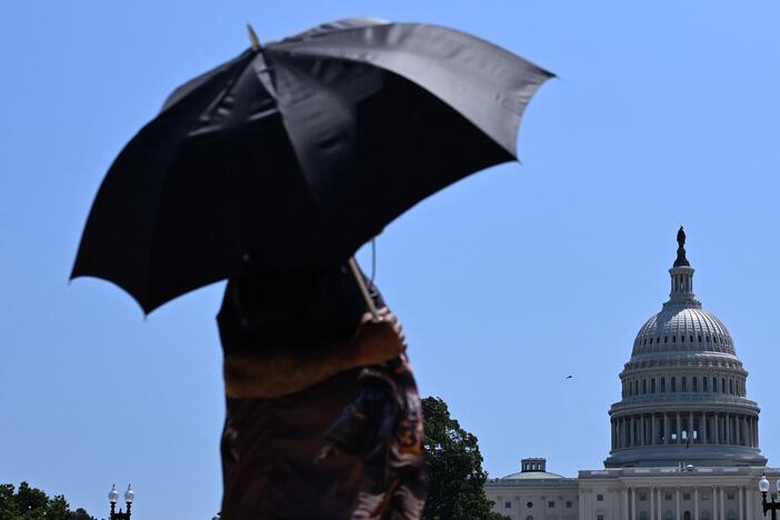 A person uses an umbrella as they walk near Capitol Hill in Washington, D.C., on Friday. The United States is experiencing its first significant heat wave of the year, across the Great Plains and expanding into parts of the Midwest and Great Lakes over the weekend, according to the National Weather Service.