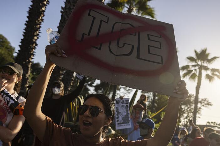 A demonstrator holds up a sign as they protest in front of the main entrance of Dodger Stadium on Thursday.