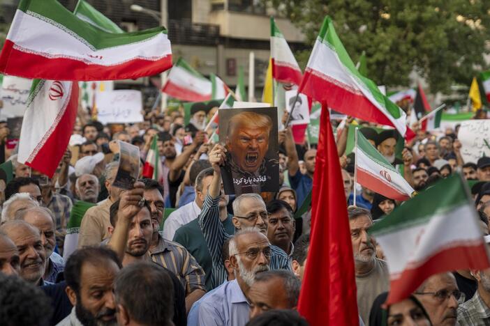Iranian protesters chant slogans and one holds a poster with a vampire-like illustration of President Trump in Tehran's Revolution Square on Sunday to protest the U.S. attacks on nuclear sites in Iran.