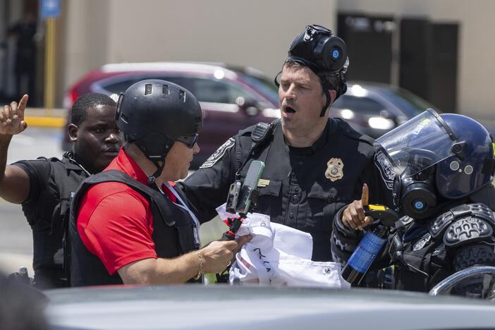Police tell Spanish-language reporter Mario Guevara (left, red shirt) to move back during a protest on Immigration and Customs Enforcement raids and deportation arrests on Chamblee Tucker Road in Atlanta on Saturday, June 14.