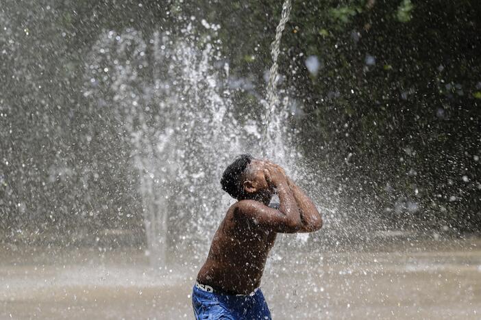 A child covers his face while a stream of water pours down at Waterfront Park on Sunday, June 22, 2025, in Louisville, Ky.