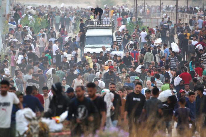 People carry relief supplies from the Gaza Humanitarian Foundation (GHF), a private U.S.-backed aid group that has bypassed the long-standing United Nations-led system in the territory, as displaced Palestinians return from an aid distribution center in the central Gaza Strip, on June 8.