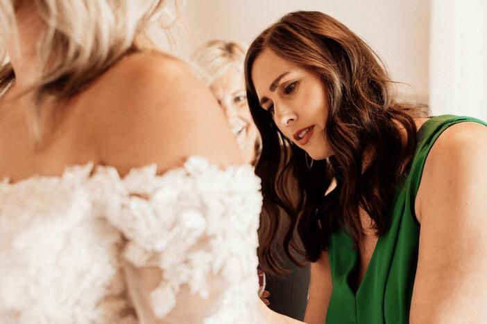 Claire Landgraf helps a bride try on a dress at her shop Finery Bridal Chic in Rochester, Minn.