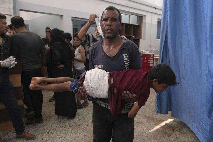 A man carries a child, who was wounded in an Israeli strike, after being treated in the Shifa Hospital, Gaza City on Monday.