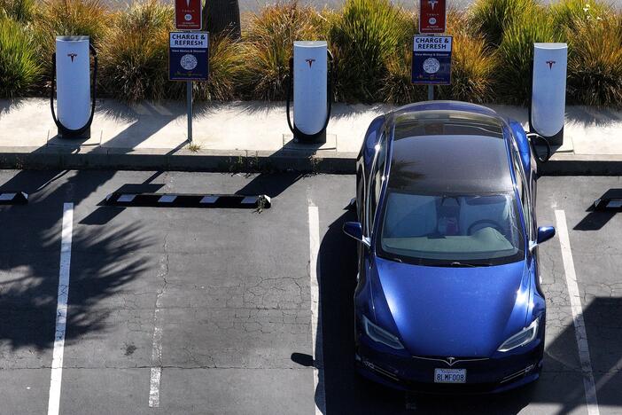 An electric vehicle sits parked at a Tesla charging station in Sausalito, Calif., in June. The tax and spending package under consideration in the Senate could eliminate federal tax credits for buying and purchasing an EV at the end of September — even sooner than a House version of the same bill proposes.