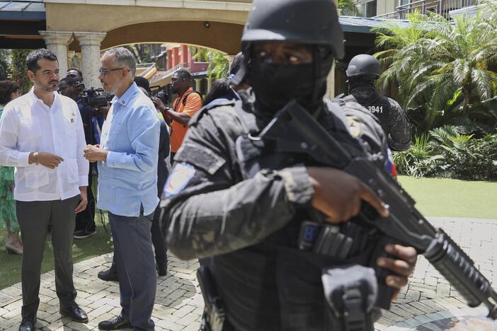 Security guards stand watch as Haiti's Prime Minister Alix Didier Fils-Aime, center, talks with the Mexico's Charge d'Affaires Jesus Cisneros after attending an event marking one year since the start of the Multinational Security Support Mission in Port-au-Prince, Haiti on Thursday.