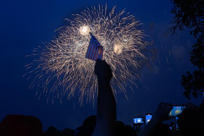 An attendee at the US Army's 250th birthday celebration parade holds up a US flag during fireworks in Washington, DC on June 14, 2025.
