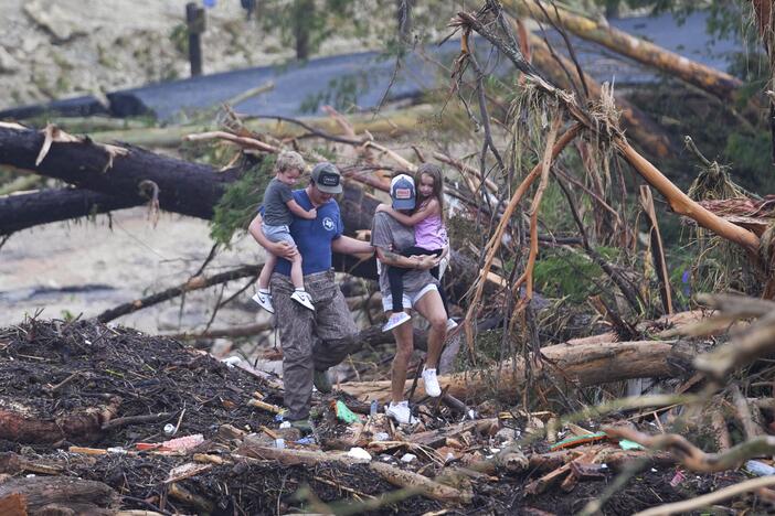 People climb over debris on a bridge atop the Guadalupe River after a flash flood swept through the area Saturday, July 5, 2025, in Ingram, Texas