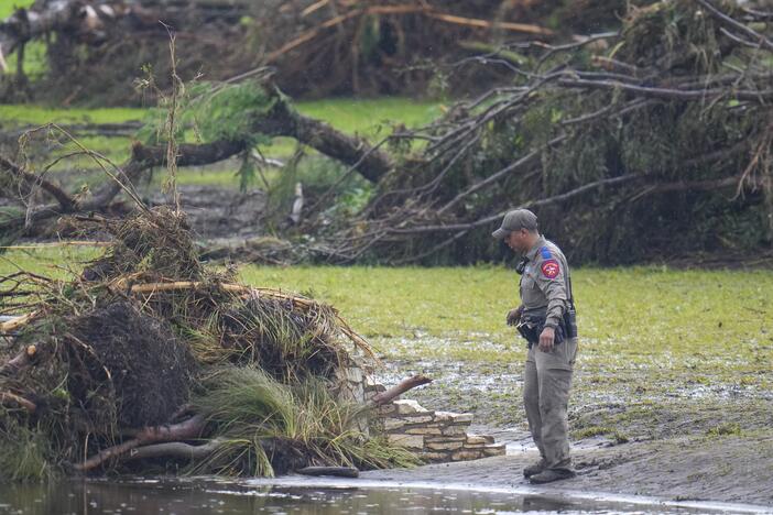 A Texas Department of Public Safety official inspects debris on the waterfront at Camp Mystic along the banks of the Guadalupe River after a flash flood swept through the area Sunday, July 6, in Hunt, Texas.