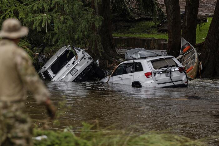 Vehicles sit submerged as a search and rescue worker looks through debris from the early July flash flooding in Hunt, Texas.