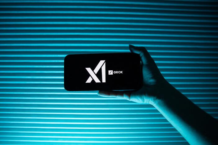A person holds a telephone displaying the logo of Elon Musk's artificial intelligence company, xAI  and its chatbot, Grok.