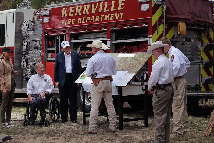 President Trump, first lady Melania Trump and Texas Governor Greg Abbott meet with local emergency services personnel as they survey flood damage along the Guadalupe River on July 11, in Kerrville, Texas.