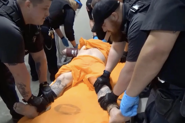 A screenshot from a video of officers at the U.S. penitentiary in Thomson, Ill., holding an incarcerated person in a four-point restraint.