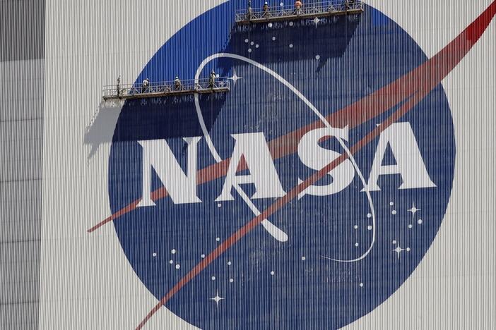 Workers on scaffolding repaint the NASA logo near the top of the Vehicle Assembly Building in 2020 at the Kennedy Space Center in Cape Canaveral, Fla.