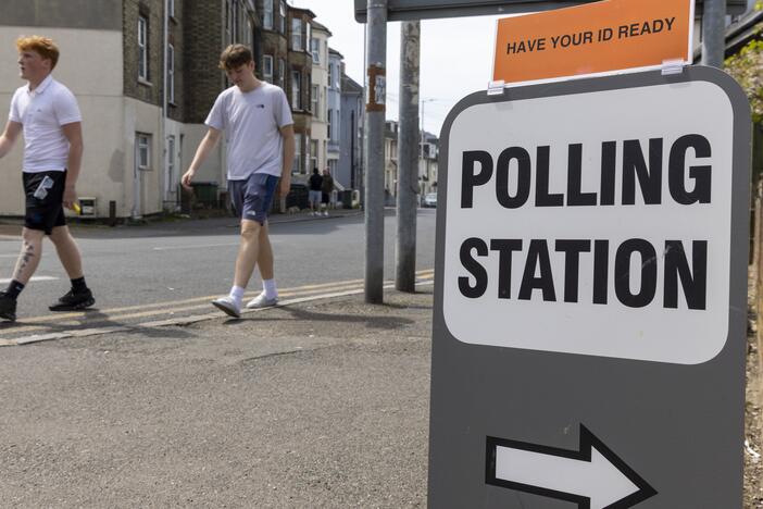 People walk past a sign for a polling station during local council elections in Folkestone, England in May. The British government is announcing plans to lower the voting age to 16.