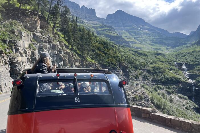 Along Glacier National Park's Going to the Sun Road, tourists admire the view from one of the park's vintage red buses