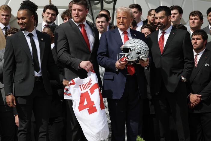 President Trump stands with Ohio State Head Coach Ryan Day (R) as he welcomed the 2025 College Football National Champions from Ohio State University to the White House during a ceremony on April 14, 2025 in Washington, DC. Trump's new executive order seeks to ban "pay-for-play" deals and requires schools to provide scholarships in women's and Olympic sports — and it dangles the threat of withholding federal funds to schools as an enforcement mechanism.