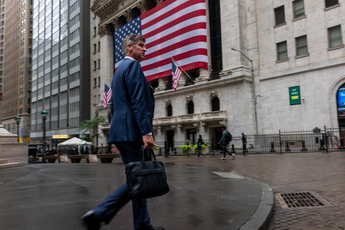 A businessman walks by the New York Stock Exchange in New York City. As more than 100 big companies reported earnings this week, the S&P 500 and Nasdaq hit a series of record highs.
