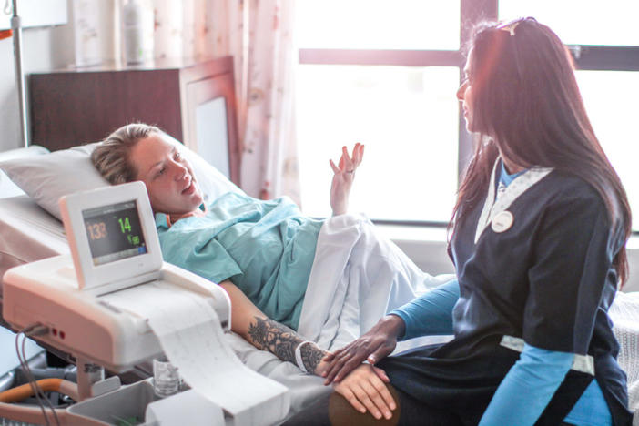 a Young pregnant woman is supported by her Doula in hospital before a caesarean section.