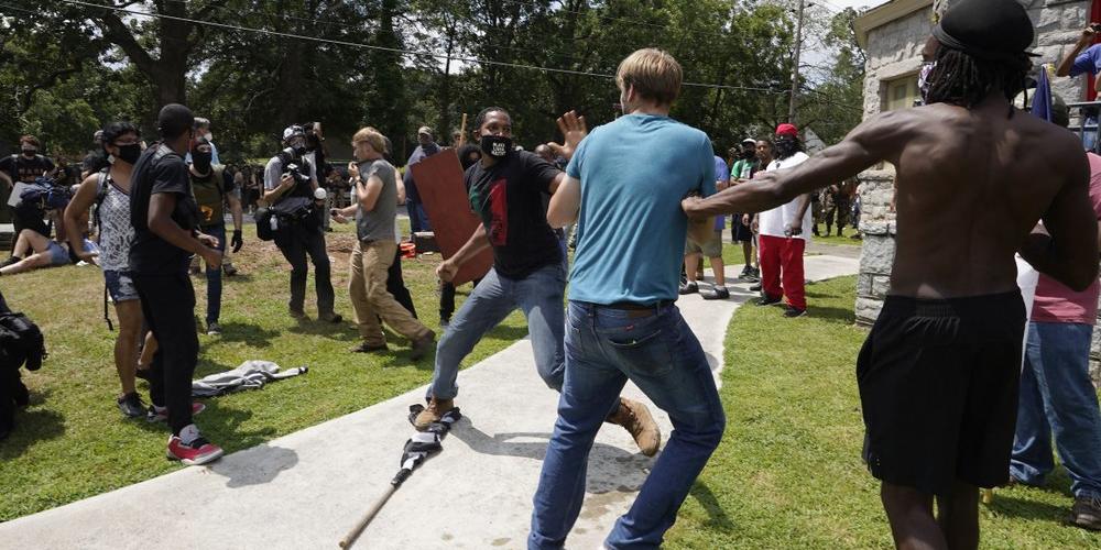 Protesters clash during a demonstration, Saturday, Aug. 15, 2020, in Stone Mountain Village, Ga. Several dozen people waving Confederate flags, many of them wearing military gear, gathered in downtown Stone Mountain where they faced off against a few hundred counterprotesters, many of whom wore shirts or carried signs expressing support for the Black Lives Matter movement.