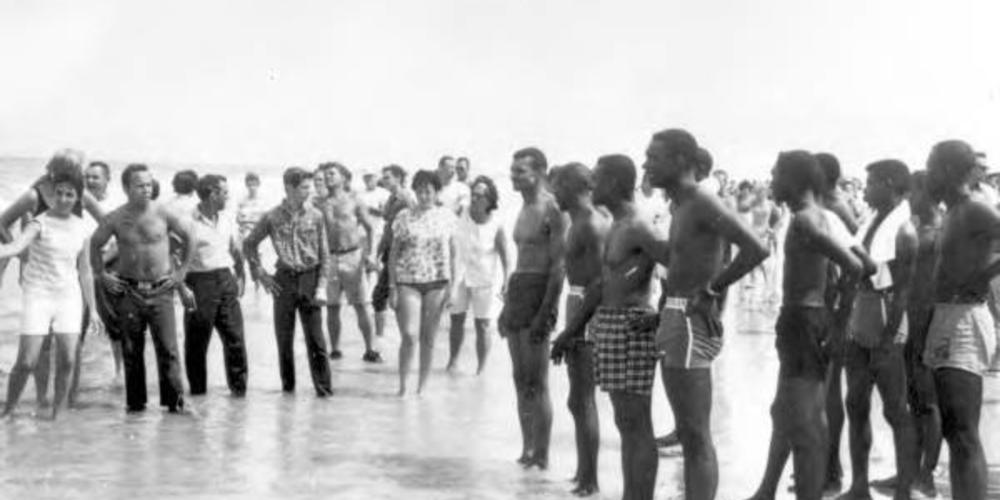 C.T. Vivian and other civil rights demonstrators stand on a beach in St. Augustine, Fl. with white counter-protestors standing nearby.