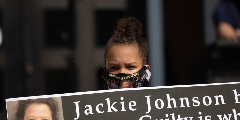 Aaliyah Trimmings, 9, holds a banner celebrating the prosecution of former district attorney Jackie Johnson, who faces charges of impeding prosecution of the men charged in Ahmaud Arbery’s death.