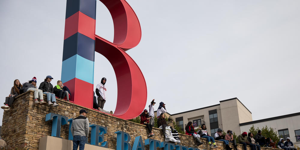 Fans scale The Battery sign outside of Truist Park to get a better view of the Braves players as they pass by during their victory parade on Nov. 5.