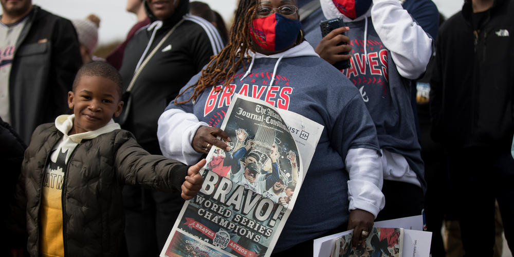 Fulton County resident Melisa Smith holds a copy of The Atlanta Journal-Constitution along the Braves parade route in Cobb County on Nov. 5.