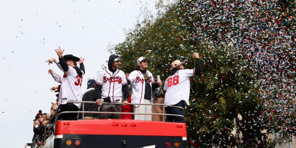 Braves players celebrate on top of a double decker bus in the midst of confetti and cheer.