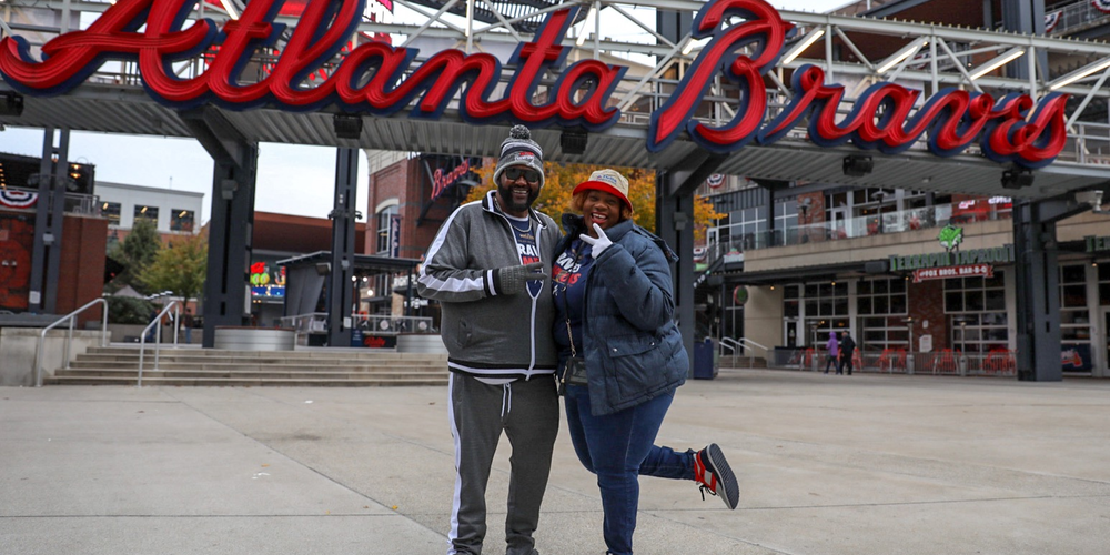 Lee and Shenelle Brown pose in front of the Atlanta Braves sign outside Truist Park. They were among the first fans to arrive early Friday, Nov. 5, 2021, to celebrate the team's World Series victory.