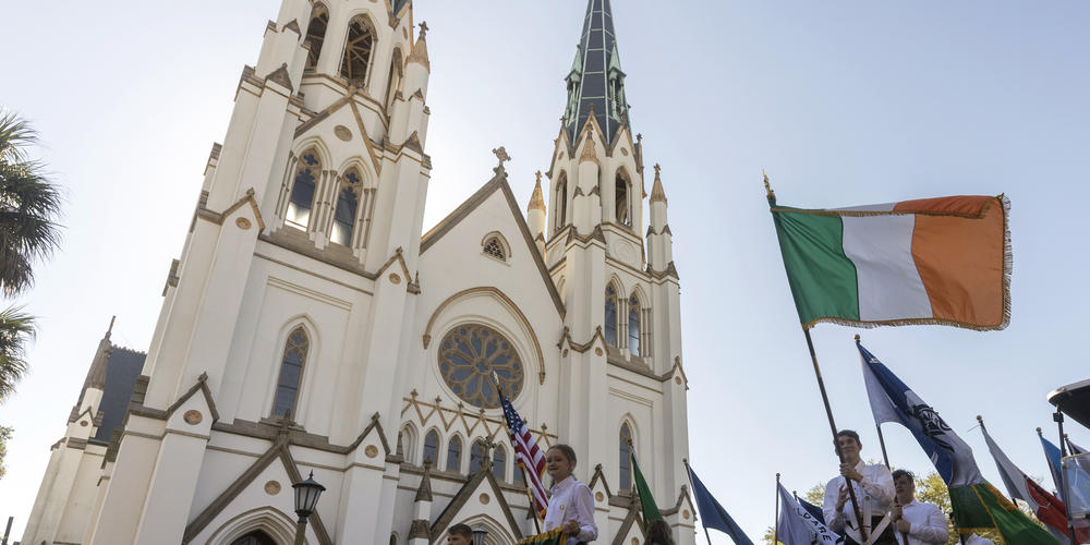 Members of the Savannah Parade Committee carry the flags of Ireland during the St. Patrick's Day parade, Thursday, March 17, 2022, in front of The Cathedral of St. John the Baptist in historic downtown Savannah, Ga. The South's largest St. Patrick's Day celebration made a big comeback following a two-year virus hiatus.