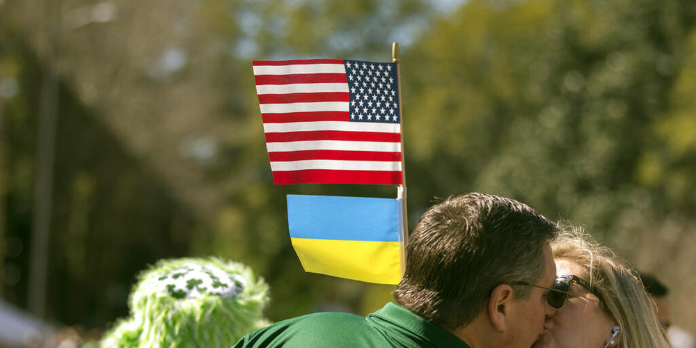 Colleen Hines, right, kisses her husband Mike Hines as he waves an American flag and Ukrainian flag during the St. Patrick's Day parade, Thursday, March 17, 2022, in Savannah, Ga.