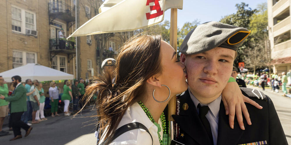 Hannah Hirsch, of Cumming, Ga., kisses a member Benedictine Military School as he marches in the St. Patrick's Day parade, Thursday, March 17, 2022, in historic downtown Savannah, Ga. The South's largest St. Patrick's Day celebration made a big comeback following a two-year virus hiatus.