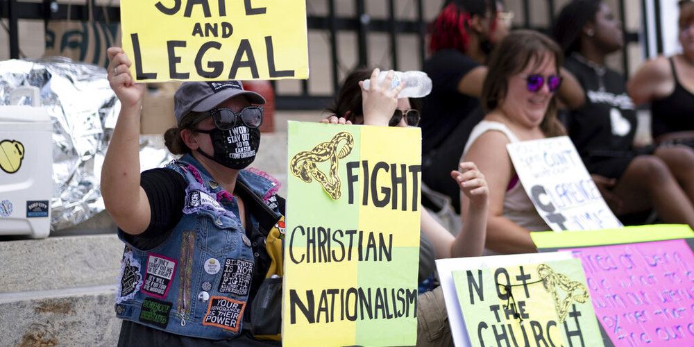 A small group, including Stephanie Batchelor, left, sits on the steps of the Georgia State Capitol protesting the overturning of Roe v. Wade on Sunday, June 26, 2022. 