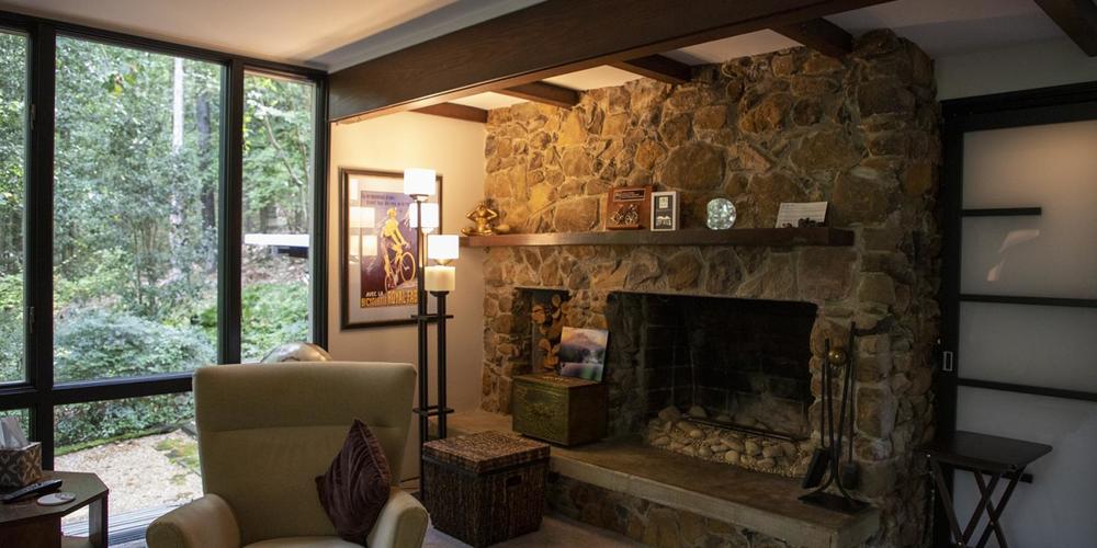 The lower living room has a stone fireplace and floor to ceiling windows.