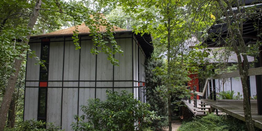 A wooden walkway leads from the carport to the house.