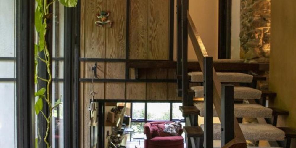 The stairs near the front door are illuminated by two-story windows.
