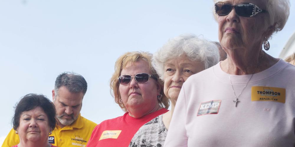 Kemp supporters listening to his brief stump speech at Macon's Middle Georgia Regional Airport on Monday.