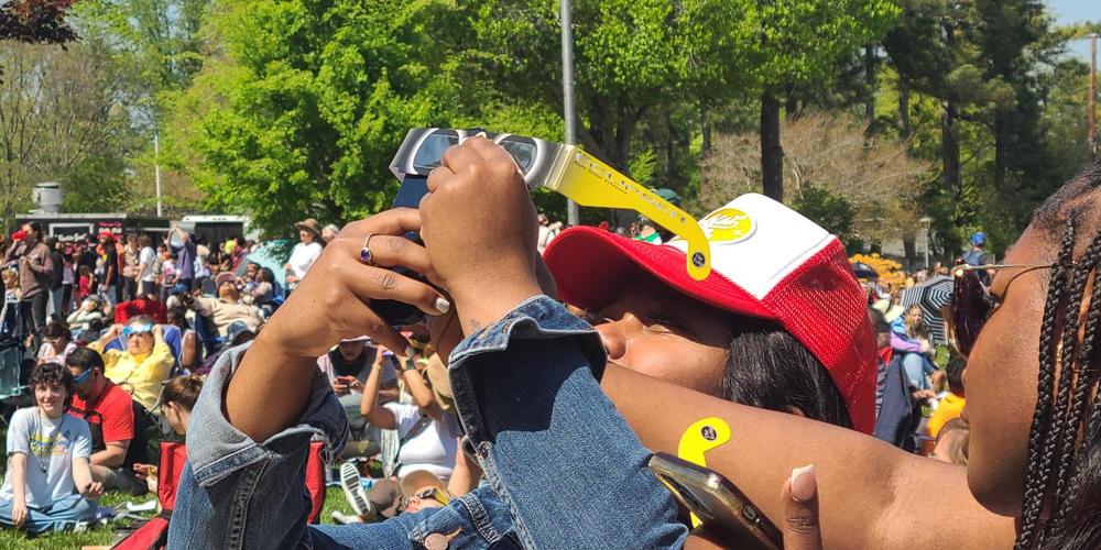 Ryan Washington uses the Fernbank Science Center eclipse viewers to take a picture of the sun on her phone in Atlanta, Ga., on April 8, 2024.