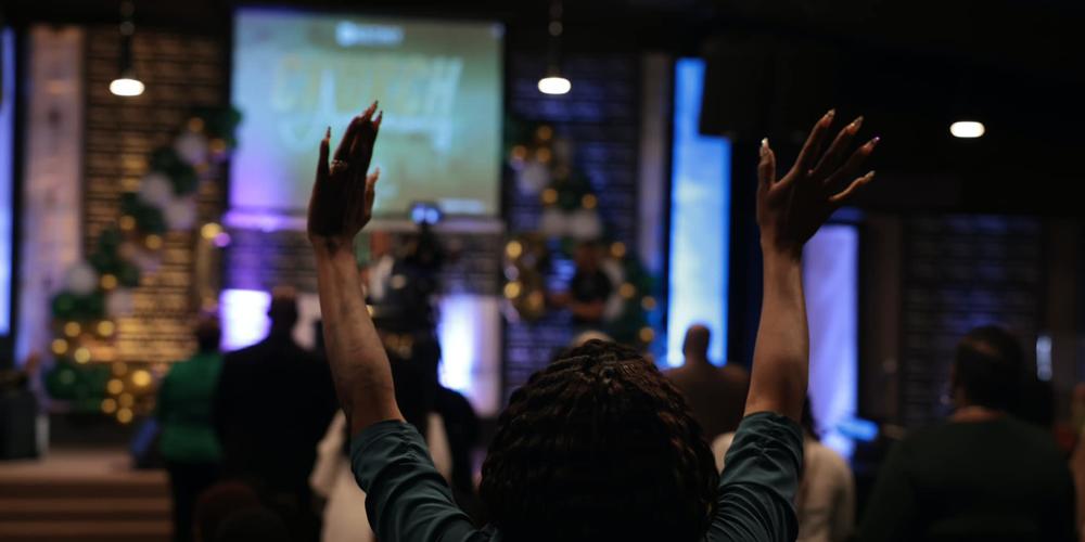 A woman raises her hands during church at Destiny Christian Center International.