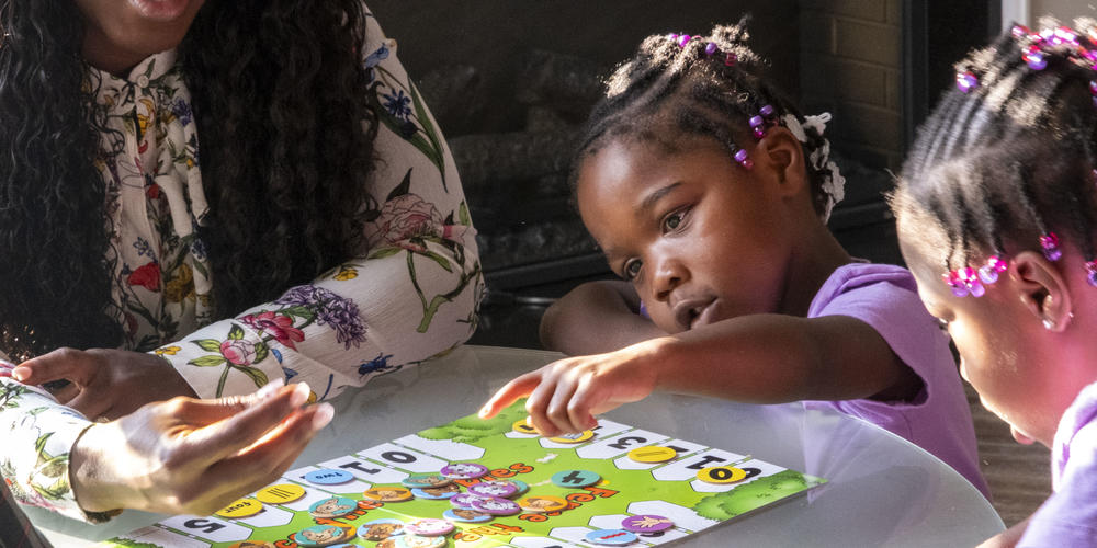 Justice, center, points to a number on the board game in front of her.