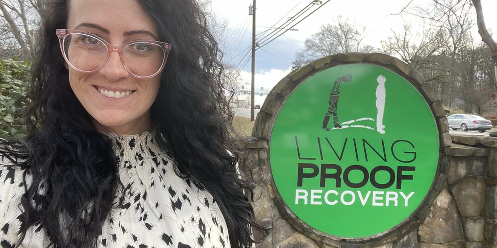 Living Proof Recovery Executive Director Brittney Galvanauskas stands by the sign outside the recovery center's sign.