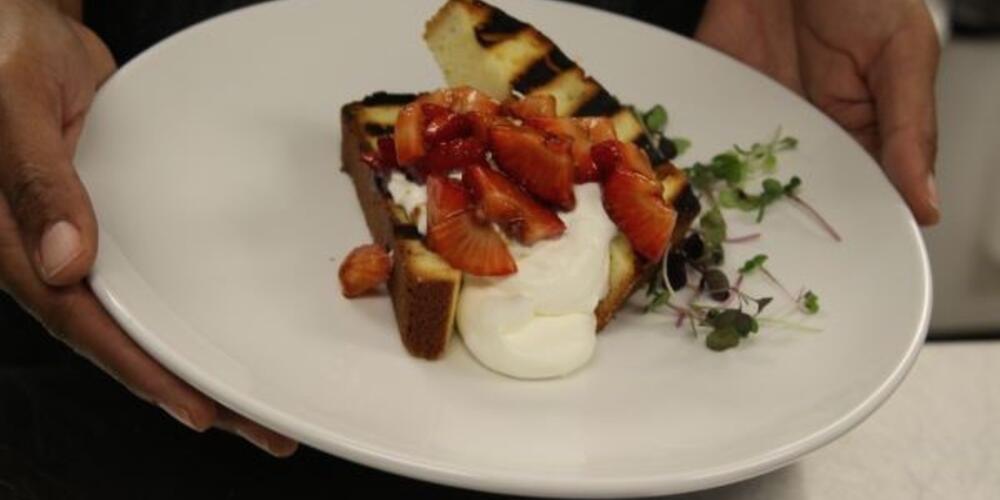 A photo of hands holding a plate of strawberry shortcake
