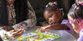 Justice, center, points to a number on the board game in front of her.