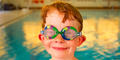 Young boy swimmer wearing goggles. Photography by Billy Howard