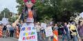 A giant paper mache woman wearing a sign saying workers rights are human rights.